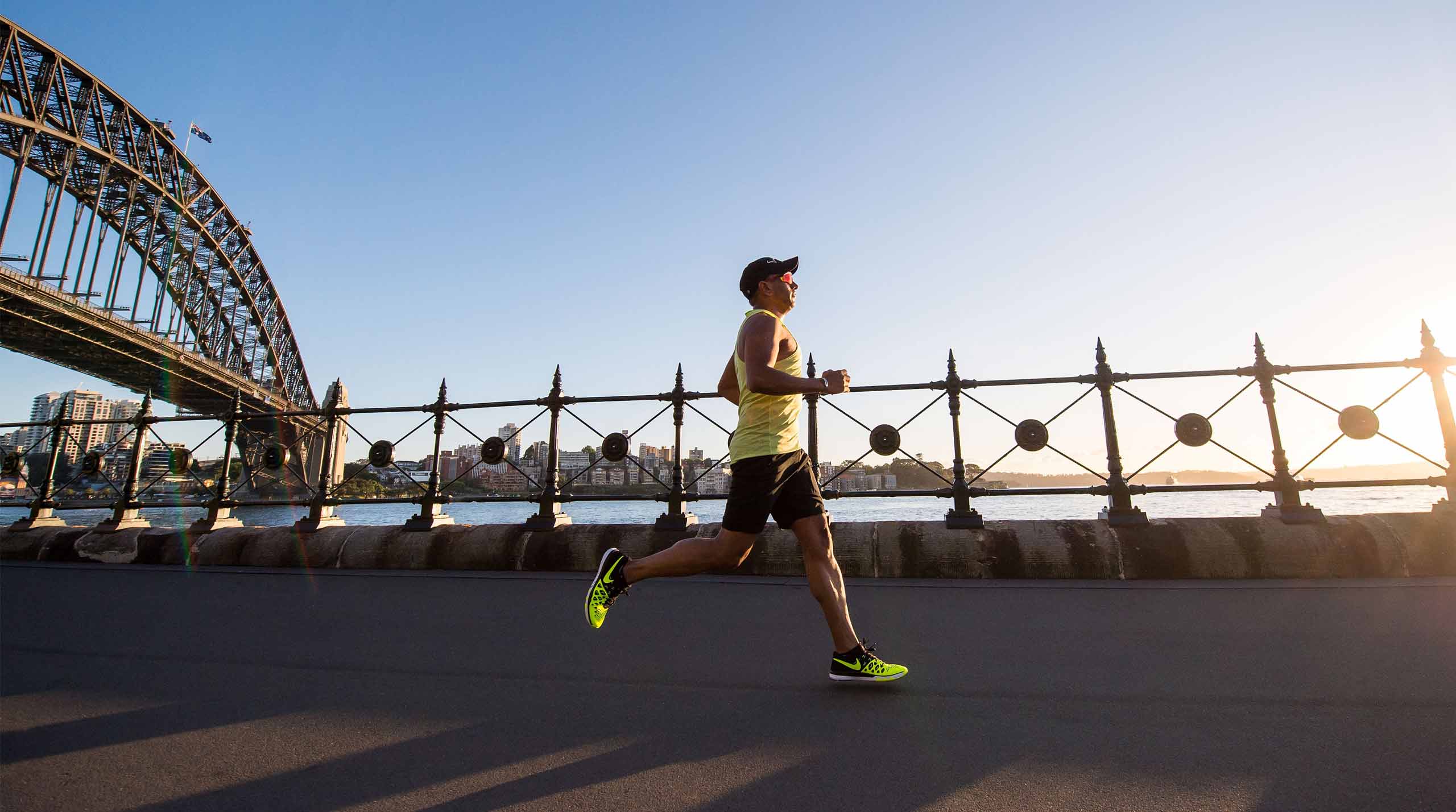 a person runs by the river in the background a city and a steel bridge can be seen